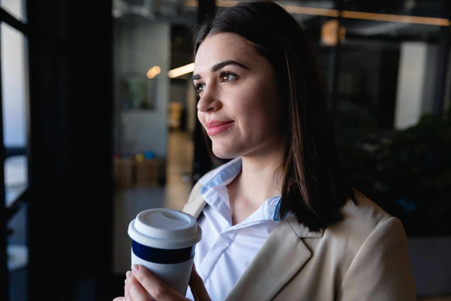 Caucasian woman looking outside and holding a mug